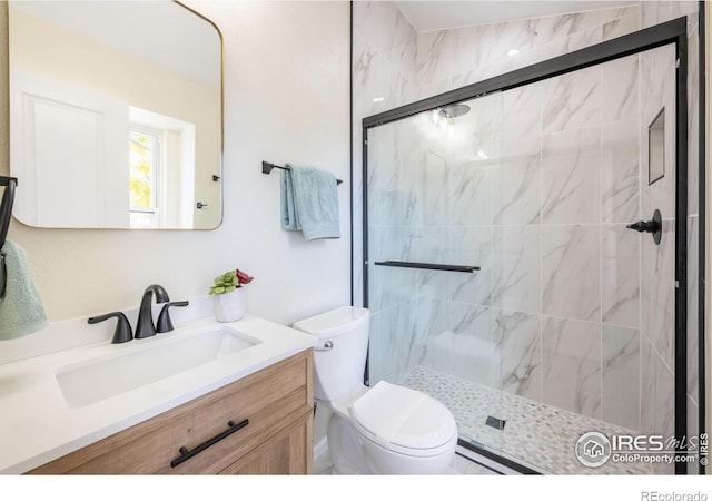 full bathroom featuring a stall shower, toilet, and vanity