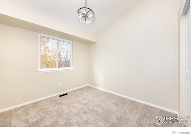 carpeted empty room with visible vents, baseboards, and lofted ceiling