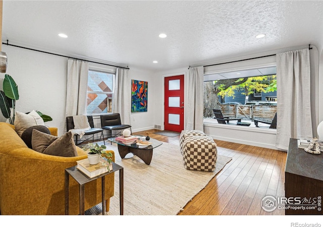 living room featuring hardwood / wood-style floors, a textured ceiling, and a healthy amount of sunlight