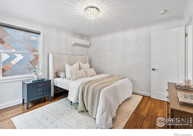 bedroom with a wall mounted air conditioner and light wood-type flooring