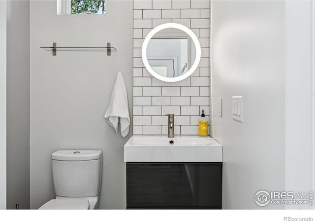 bathroom with vanity, decorative backsplash, and toilet