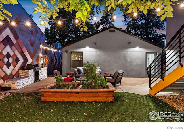 patio terrace at dusk featuring grilling area, a yard, and a fireplace