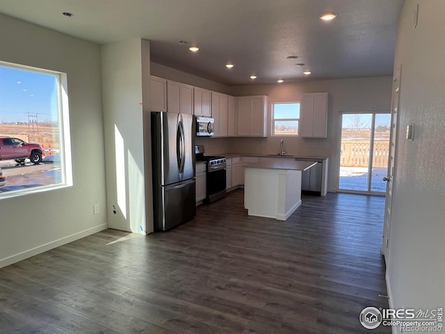 kitchen featuring a kitchen island, appliances with stainless steel finishes, white cabinetry, sink, and dark wood-type flooring