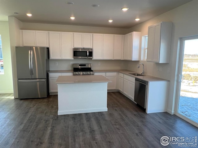 kitchen featuring sink, dark wood-type flooring, appliances with stainless steel finishes, a center island, and white cabinets