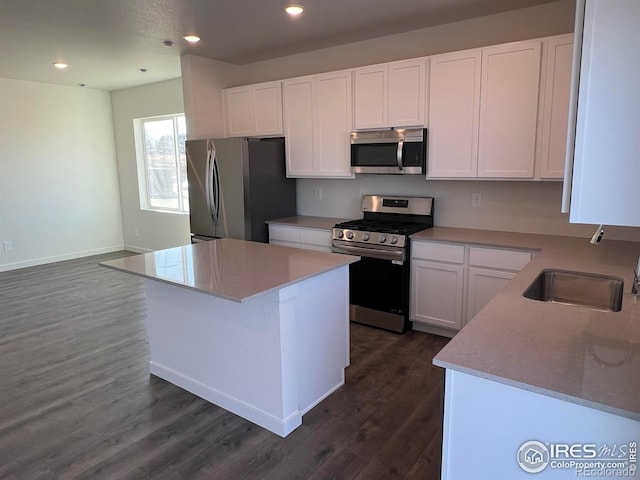 kitchen with dark wood-type flooring, stainless steel appliances, light stone countertops, white cabinets, and a kitchen island