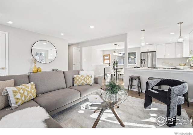 living room with light wood-style floors, baseboards, and recessed lighting