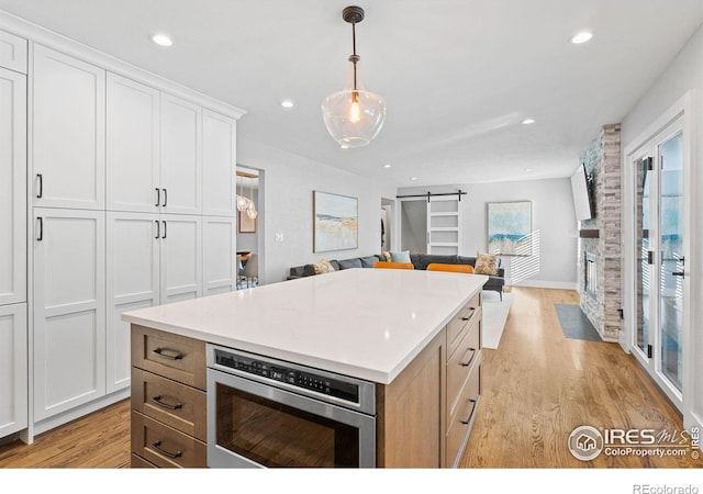 kitchen featuring a kitchen island, pendant lighting, white cabinets, a barn door, and light wood-type flooring