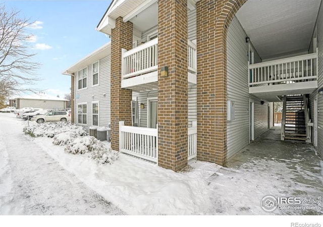 snow covered property featuring cooling unit and a balcony