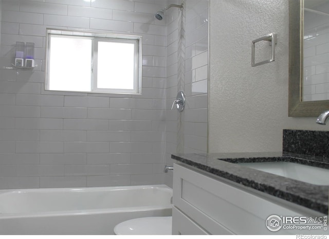 full bathroom with vanity, tiled shower / bath, and toilet