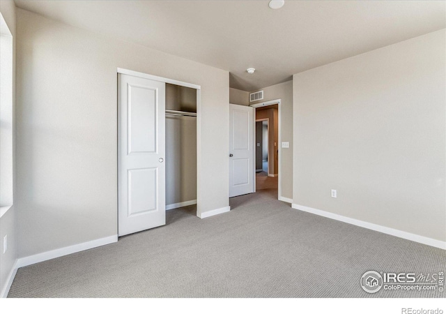 unfurnished bedroom with light carpet and a closet