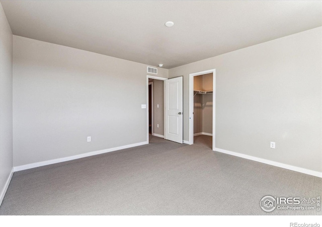 unfurnished bedroom featuring carpet, a spacious closet, and a closet