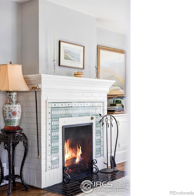 details with hardwood / wood-style flooring and a brick fireplace