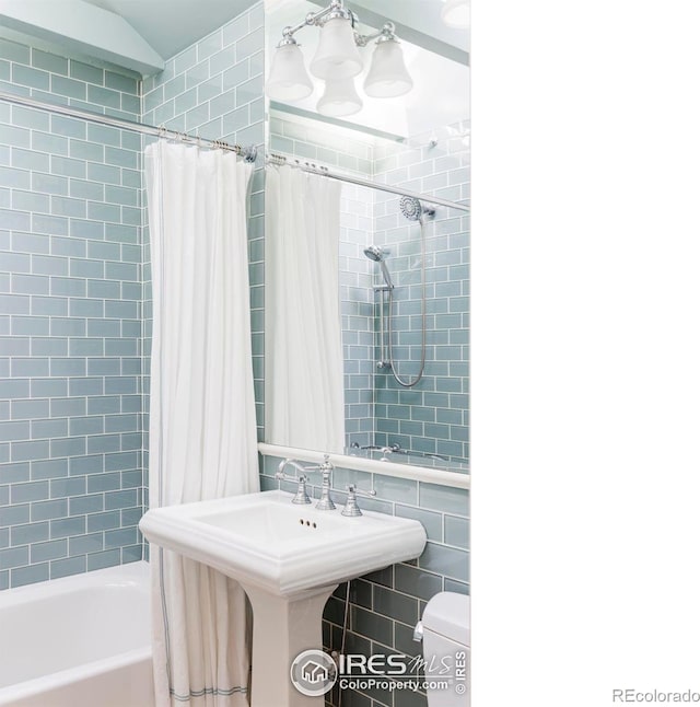 full bathroom with shower / bathtub combination with curtain, sink, toilet, and tile walls