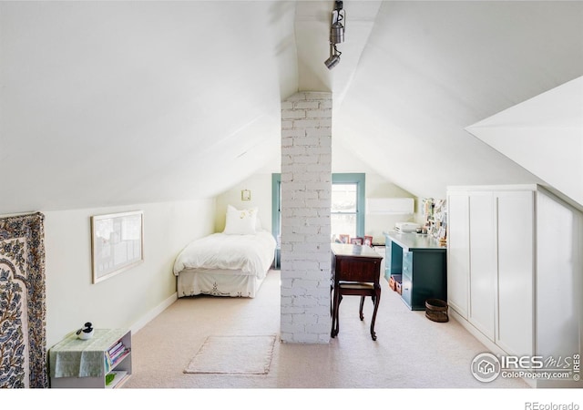 carpeted bedroom with lofted ceiling and rail lighting