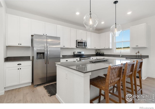 kitchen featuring stainless steel appliances, white cabinetry, and a center island