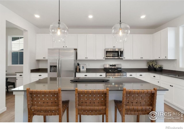 kitchen with a center island, stainless steel appliances, decorative light fixtures, and a breakfast bar