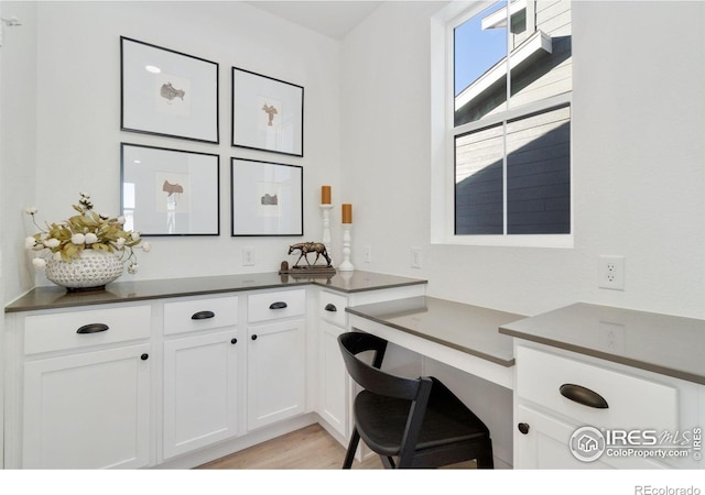 office with built in desk and light hardwood / wood-style flooring