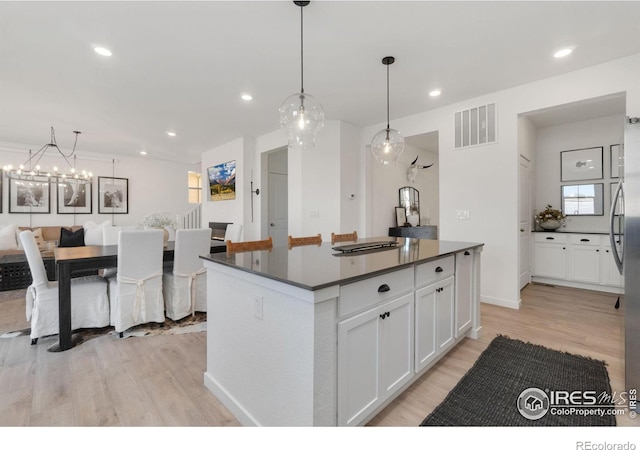 kitchen with white cabinetry, pendant lighting, light hardwood / wood-style floors, and a kitchen island