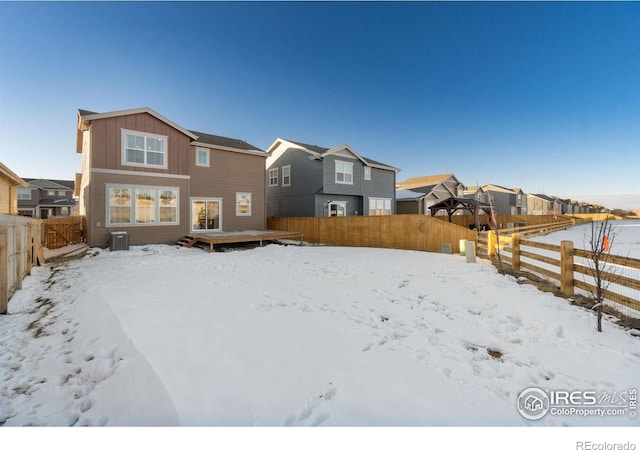 snow covered house featuring central AC