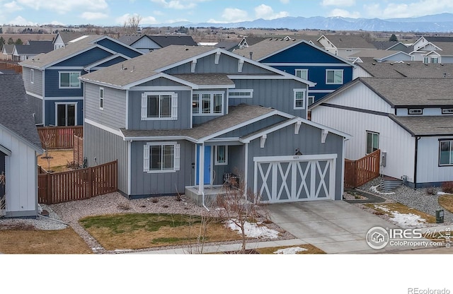 view of front facade featuring a mountain view, concrete driveway, fence, and a residential view