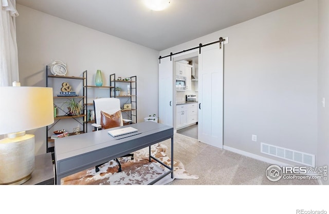 office area featuring light carpet, a barn door, and visible vents