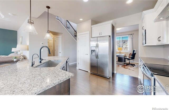 kitchen featuring decorative light fixtures, appliances with stainless steel finishes, white cabinets, a sink, and light stone countertops