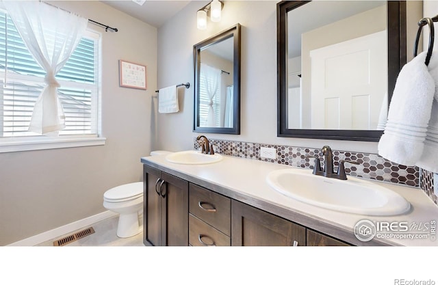 bathroom featuring visible vents, a sink, toilet, and double vanity