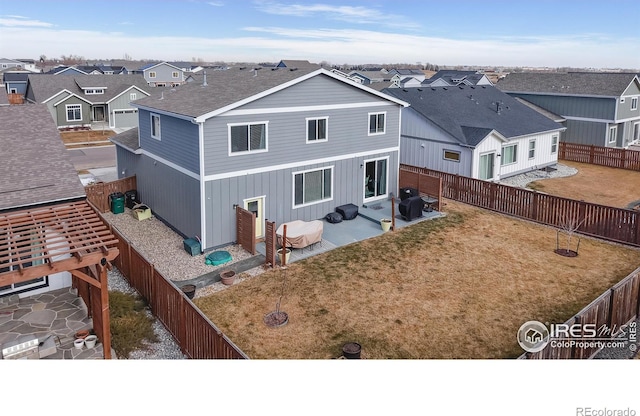 rear view of house featuring a residential view, a fenced backyard, and a lawn