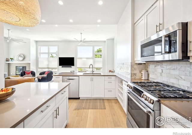 kitchen featuring sink, white cabinets, ceiling fan, stainless steel appliances, and light hardwood / wood-style flooring