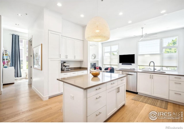 kitchen with sink, light hardwood / wood-style flooring, dishwasher, white cabinetry, and decorative light fixtures