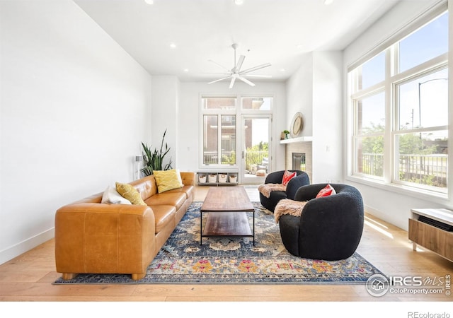 living room with a healthy amount of sunlight, ceiling fan, and light hardwood / wood-style flooring