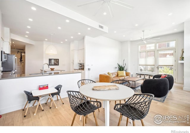 dining space with ceiling fan, sink, and light hardwood / wood-style floors