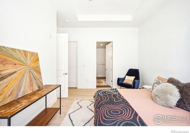 bedroom featuring a tray ceiling and light hardwood / wood-style flooring