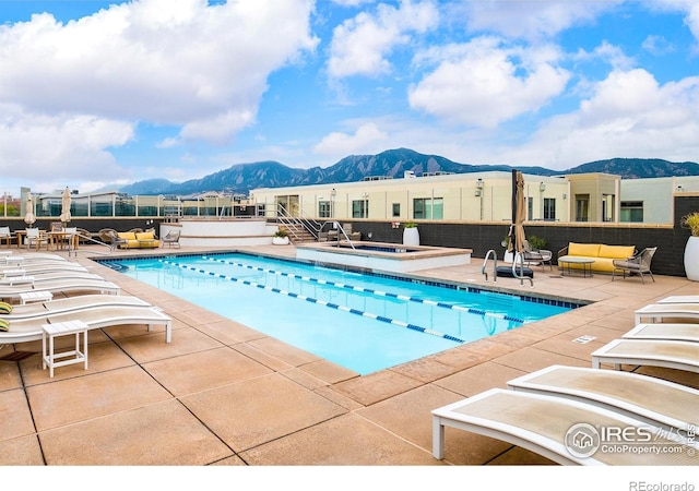 view of swimming pool with a community hot tub, an outdoor living space, a mountain view, and a patio area