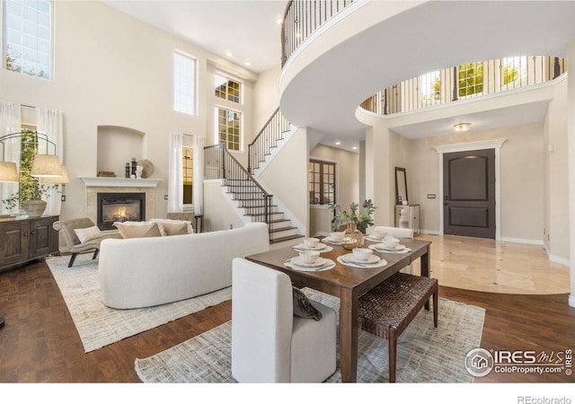 dining space featuring dark hardwood / wood-style flooring, a fireplace, a high ceiling, and plenty of natural light