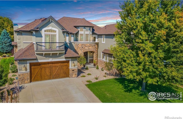 view of front of home with a garage, a yard, and a balcony