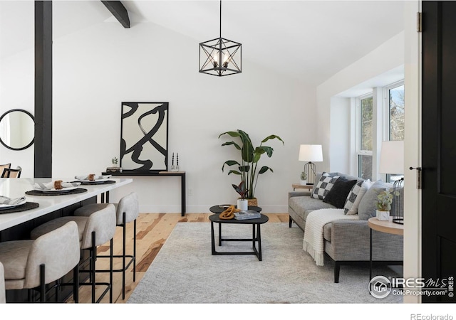 living room with light hardwood / wood-style flooring, a chandelier, and lofted ceiling with beams