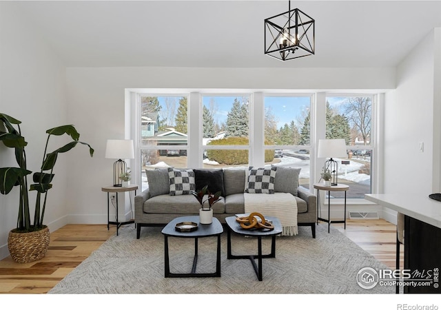 living room with plenty of natural light, an inviting chandelier, and light hardwood / wood-style flooring