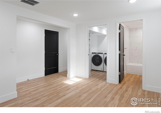 laundry area featuring independent washer and dryer and light hardwood / wood-style floors