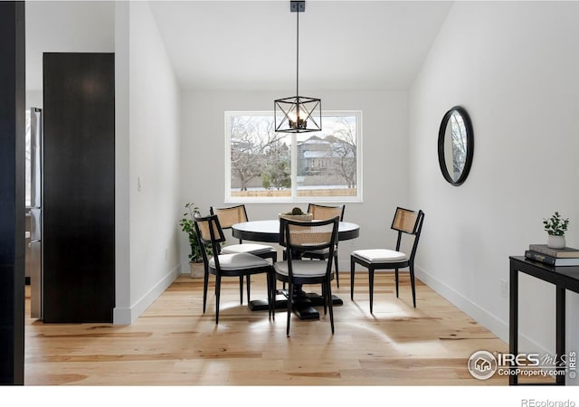 dining space with light wood-type flooring and an inviting chandelier