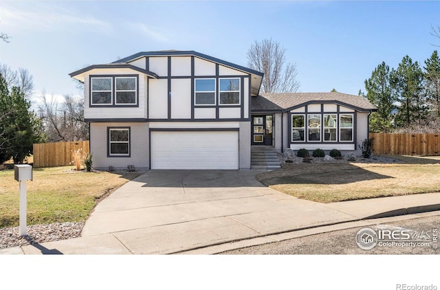 tudor home with brick siding, fence, concrete driveway, a front yard, and a garage