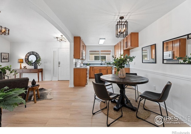 dining area featuring sink, a chandelier, and light hardwood / wood-style floors