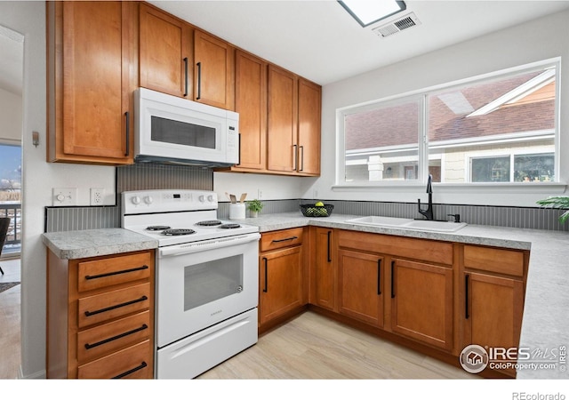 kitchen with sink, white appliances, and light hardwood / wood-style floors