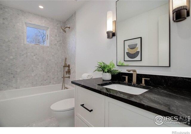 full bathroom featuring tiled shower / bath, vanity, and toilet