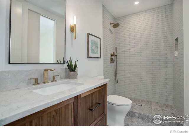 bathroom with vanity, toilet, and a tile shower