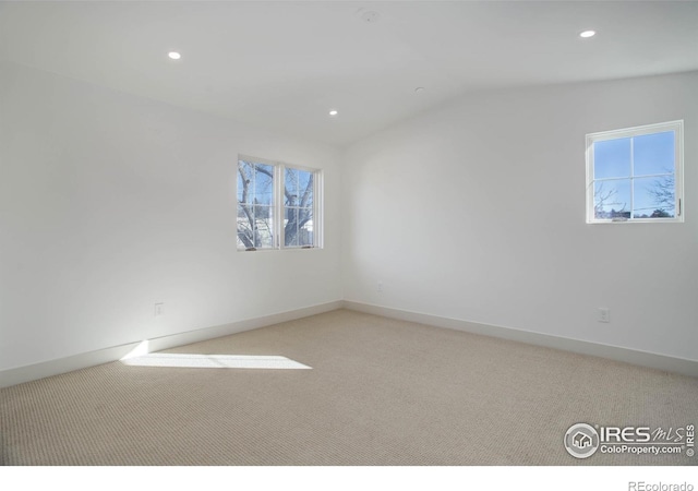 carpeted spare room featuring lofted ceiling and a healthy amount of sunlight