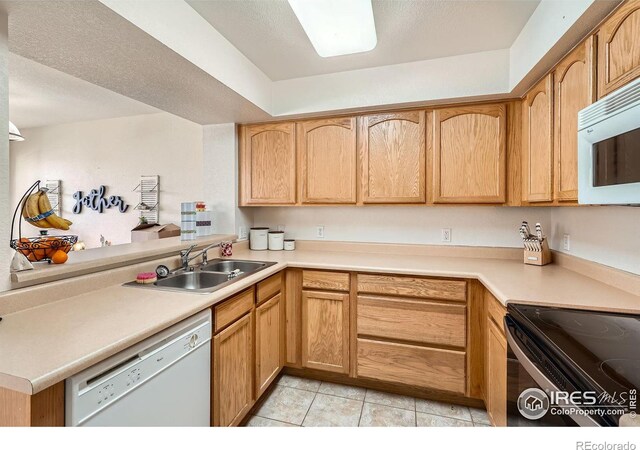 kitchen featuring sink, light tile patterned floors, white appliances, and kitchen peninsula