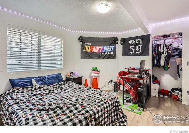 bedroom featuring wood-type flooring, a textured ceiling, and a closet