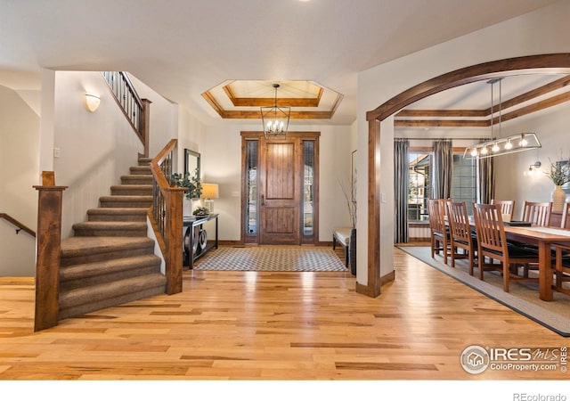 entrance foyer featuring light hardwood / wood-style flooring, a chandelier, and a tray ceiling