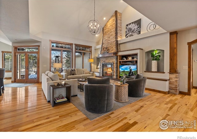 living room featuring french doors, an inviting chandelier, high vaulted ceiling, light wood-type flooring, and a fireplace